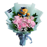 Graduation flower delivery bouquet with pink roses, baby's breath, and a teddy bear