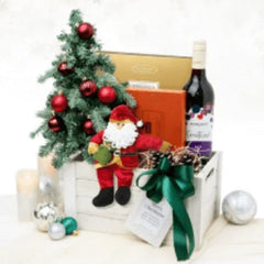Christmas-themed flower delivery gift set with mini tree, wine, Santa plush, and festive decor