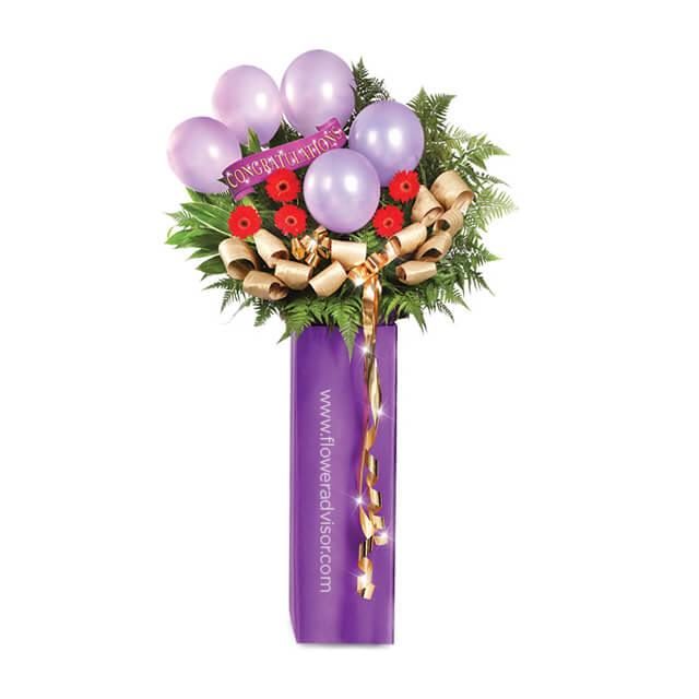 Grand opening flower stand with red flowers, purple balloons, and gold ribbon for delivery