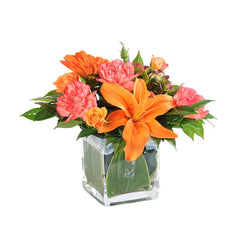 Fresh orange lily, orange roses and pink carnations in glass vase, flower delivery arrangement