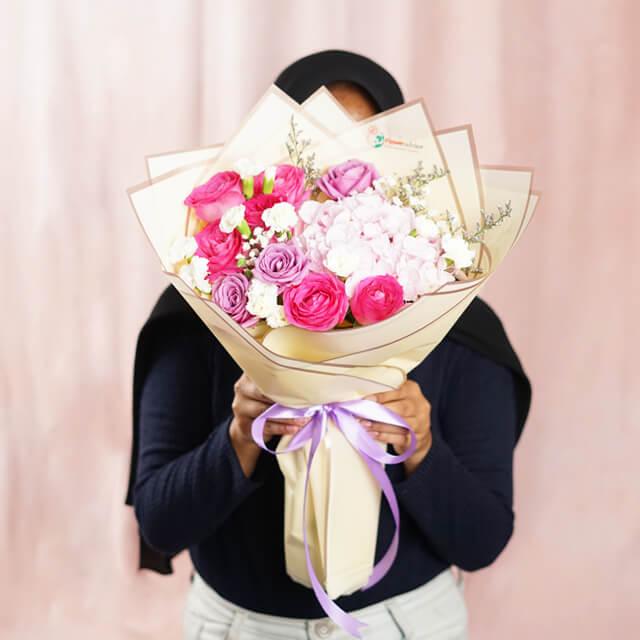 Hand holding a pink and purple flower bouquet, perfect for same-day flower delivery.