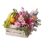 Fresh flower and fruit delivery crate with pink lilies, roses, bananas, grapes, and orange