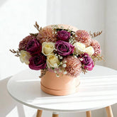 Elegant flower arrangement with purple and cream roses in a round box for flower delivery