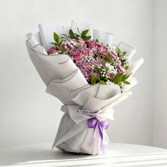 Elegant flower delivery bouquet with pink roses, white baby's breath, and purple ribbon.