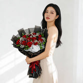 Woman holding bouquet of red roses and white flowers for flower delivery