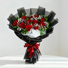 Red roses bouquet with baby's breath, wrapped in black paper and red ribbon for flower delivery