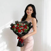 Woman holding elegant bouquet of red roses, perfect for flower delivery in Singapore