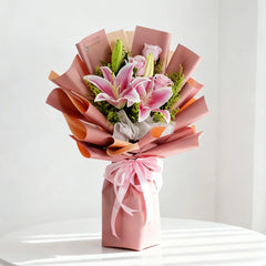 Elegant pink lily and rose bouquet for flower delivery, wrapped in pastel paper with ribbon.