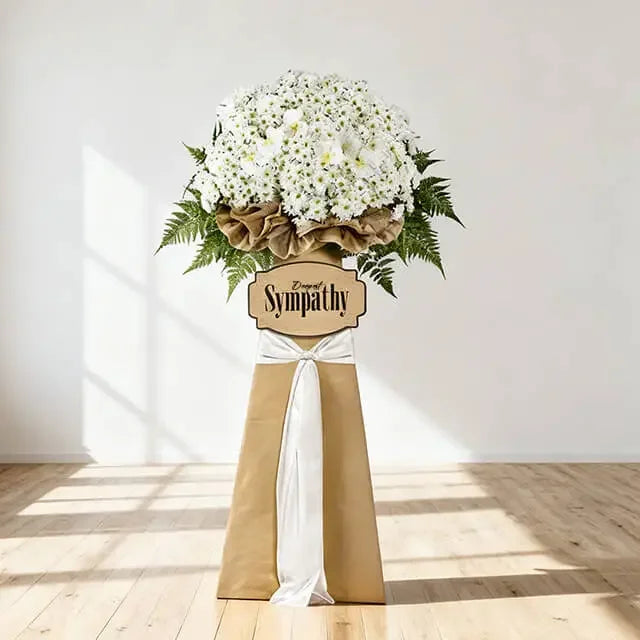 Large white sympathy flower stand with fresh blooms and greenery for condolence flower delivery