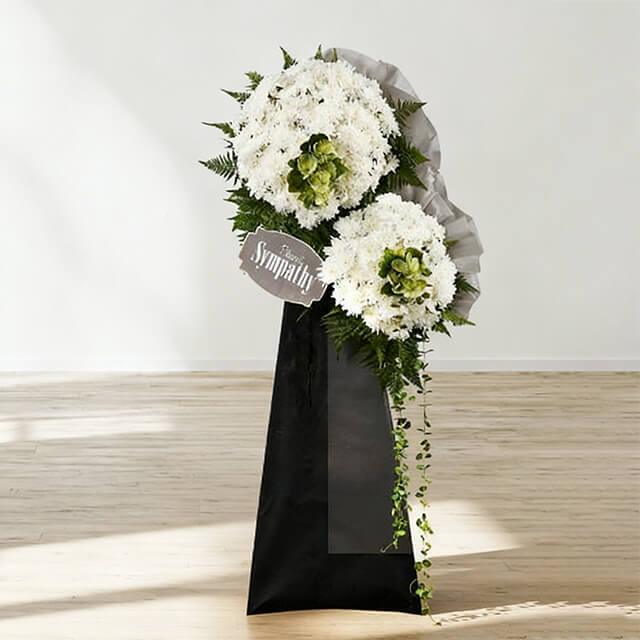 White funeral flower stand with greenery for sympathy flower delivery