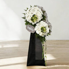 White funeral flower stand with greenery for sympathy flower delivery