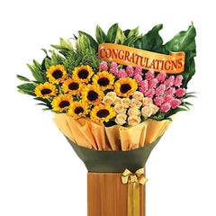 Flower delivery of a vibrant bouquet with sunflowers, roses, pink flowers and congratulations sign