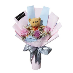 Hand bouquet with purple roses, baby's breath, and a teddy bear for flower delivery