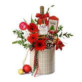 Christmas flower delivery basket with red gerbera, bottle of wine, pinecones, and festive decor