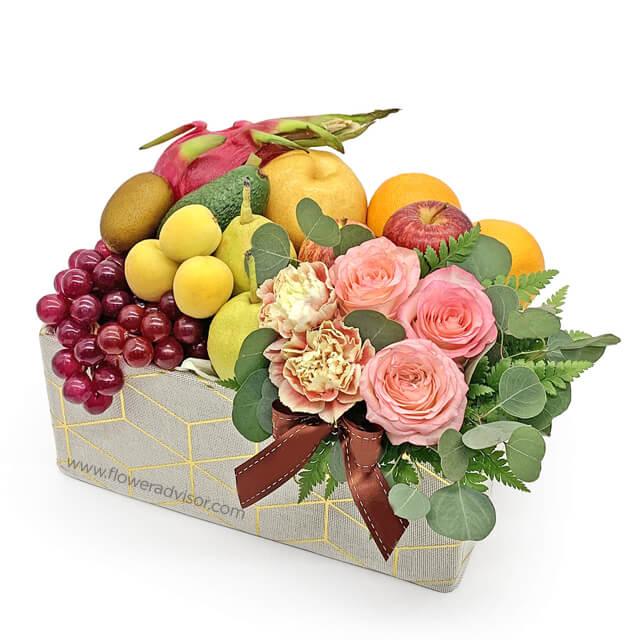 Flower delivery basket with pink roses, carnations, fresh fruits, and greenery arrangement