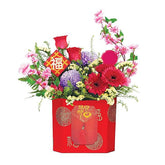 Festive flower arrangement with roses, gerberas, and mixed blooms in a red box for delivery