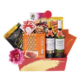 Festive flower delivery hamper with pink flower, snacks, wine bottles, and gift packets