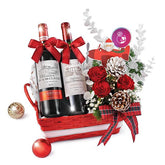 Festive flower delivery basket with red roses, pine cones, and two wine bottles.