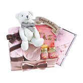 Flower delivery gift hamper with teddy bear, pink floral items, bow and congratulations tag