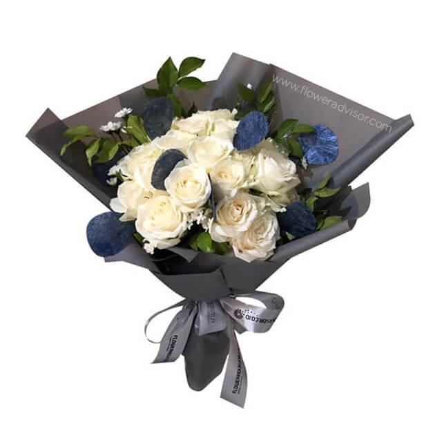 Elegant white rose bouquet for flower delivery, wrapped with greenery and blue accents