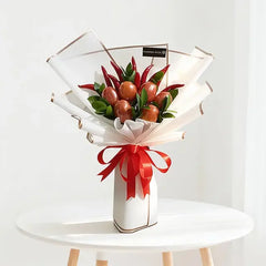 Festive fruit bouquet with red apples & chili peppers, wrapped in white paper with red ribbon, perfect for flower delivery gifts
