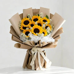 Bright sunflower bouquet with white filler flowers, wrapped in brown paper for same-day flower delivery