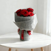Bouquet of imported red roses wrapped in grey paper, perfect for flower delivery