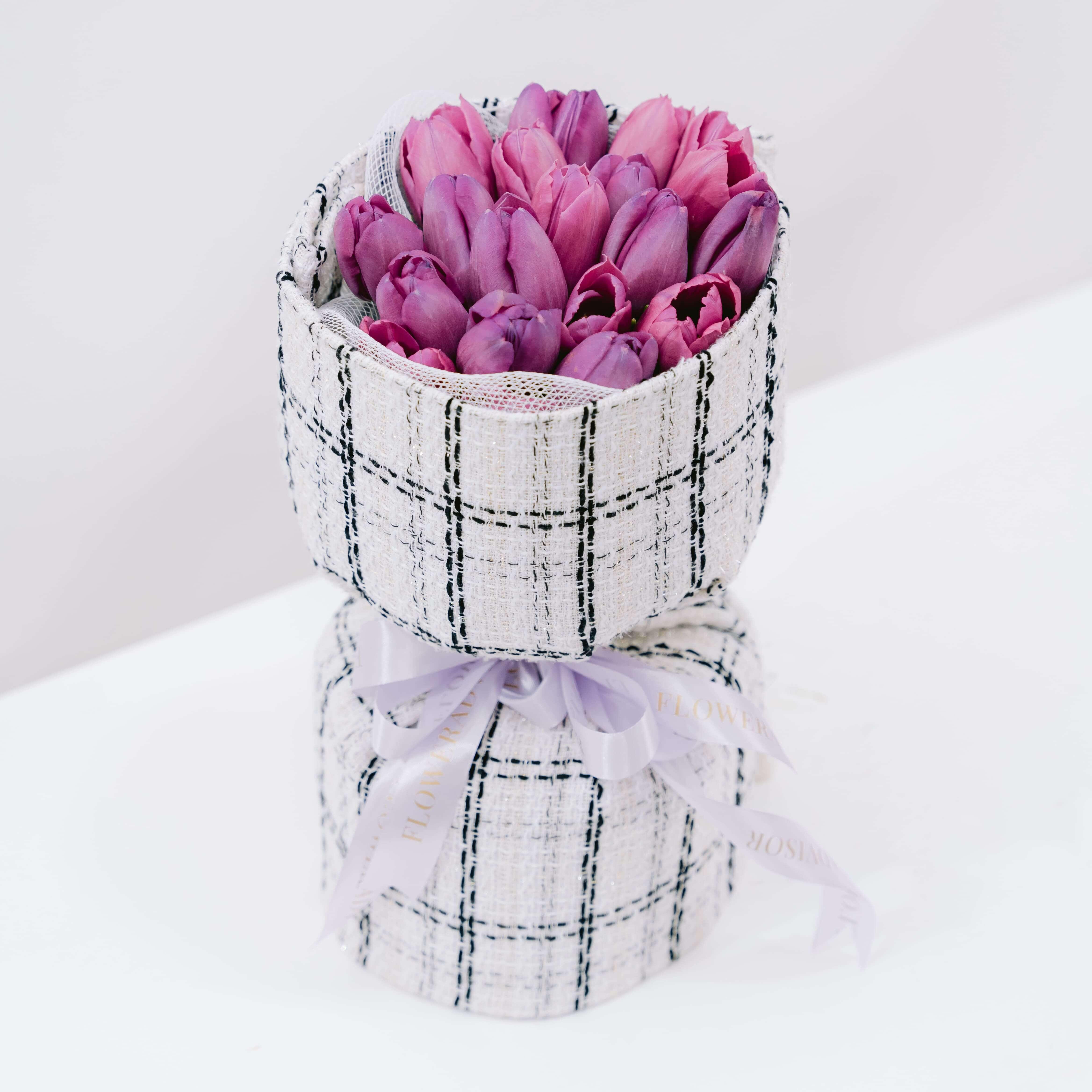 Elegant bouquet of fresh purple tulips in a checked fabric wrapper for flower delivery