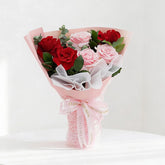 Elegant bouquet of red and pink roses with greenery for flower delivery