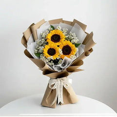 Sunflower bouquet with white filler flowers, wrapped in brown paper for flower delivery