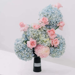 Blue hydrangeas and pink roses bouquet in a black vase for flower delivery