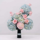Elegant flower delivery bouquet with blue hydrangeas and pink roses in a black vase
