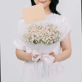 Hand holding baby’s breath bouquet with card, ideal for flower delivery gifts