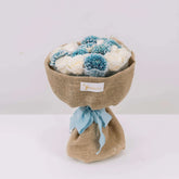 Rustic bouquet with blue and white flowers wrapped in burlap, ideal for flower delivery