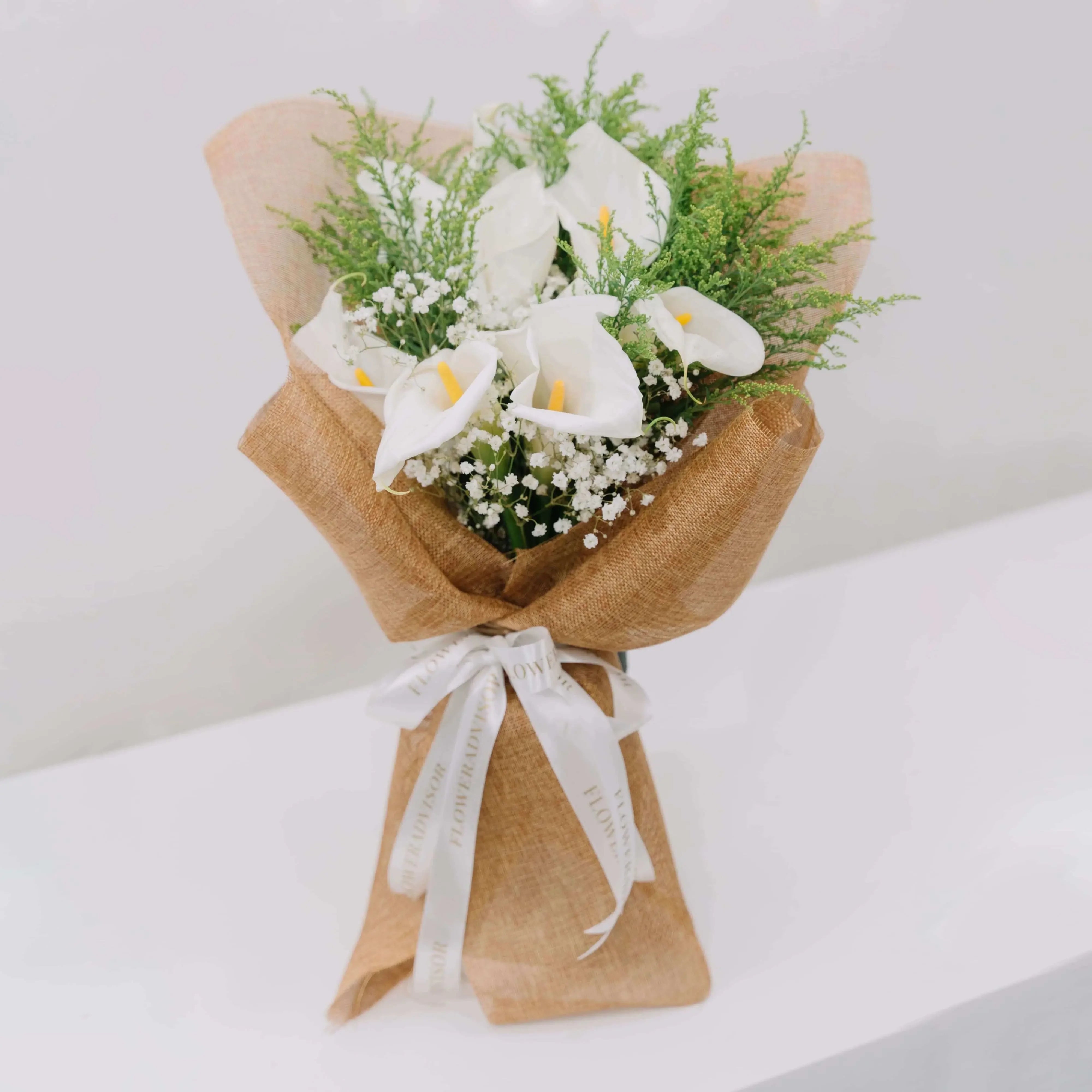 Elegant calla lily bouquet with greenery and baby's breath, ideal for flower delivery