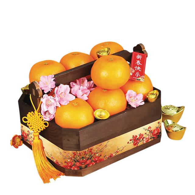 Festive flower hamper with mandarin oranges, fresh pink blossoms, and gold ingots for delivery