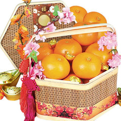 Floral gift basket with fresh oranges, pink flowers, and festive gold accents for delivery
