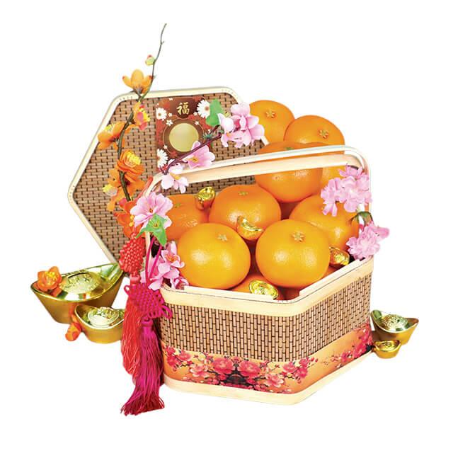 Festive flower delivery basket with mandarin oranges, pink blossoms, and gold ingots
