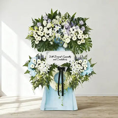 Sympathy flower stand with white lilies, chrysanthemums, and condolence message for delivery.