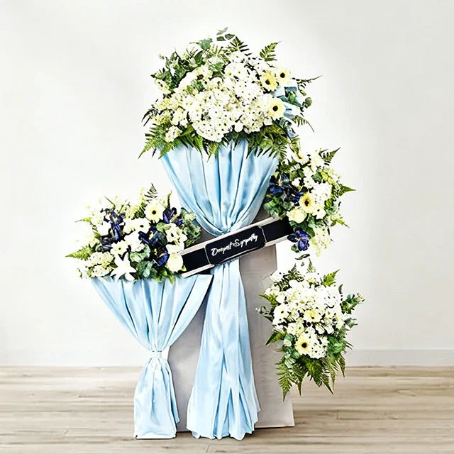 Sympathy flower stand with white and blue blooms for funeral flower delivery Singapore