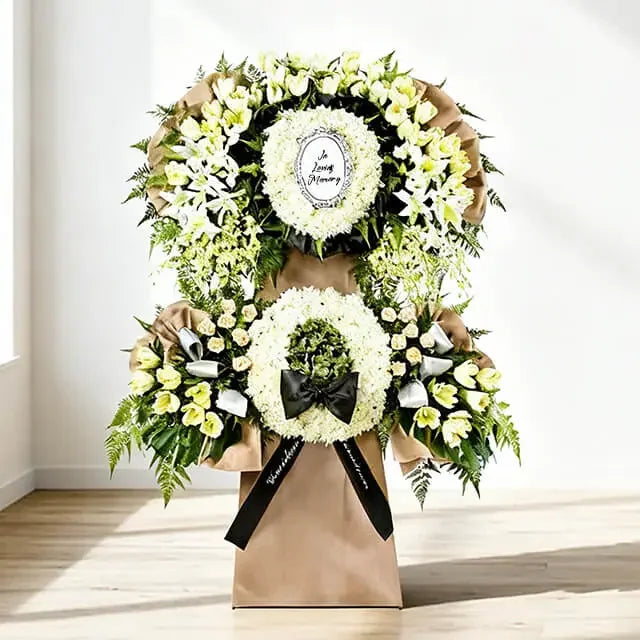 Elegant white sympathy flower stand with lilies, roses, and greenery for delivery