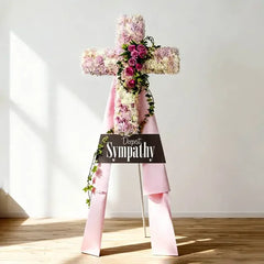 Sympathy flower delivery with pink and white cross-shaped floral arrangement and ribbon