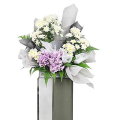 Elegant flower arrangement with white and purple blooms in a tall vase for delivery