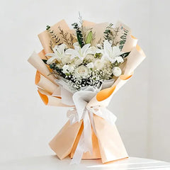 Elegant white lily and rose bouquet wrapped in peach paper, perfect for flower delivery