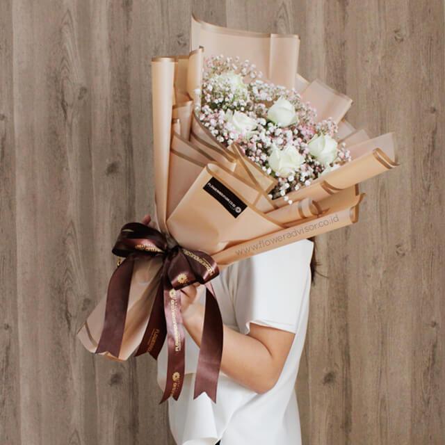 Woman holding elegant bouquet of white roses and baby's breath for flower delivery