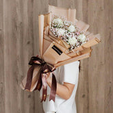 Woman holding elegant bouquet of white roses and baby's breath for flower delivery