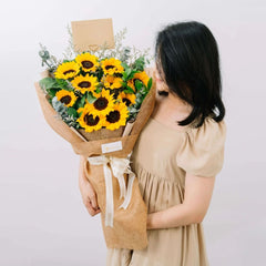 Woman holding bouquet of sunflowers and greenery for flower delivery