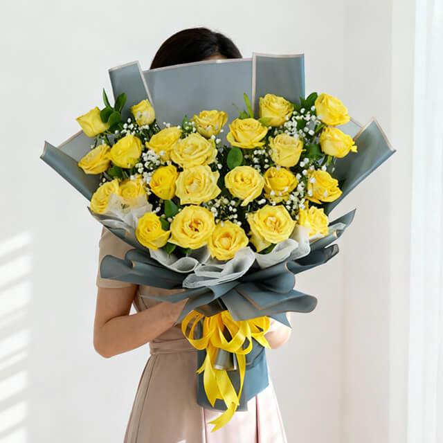 Flower delivery of a large bouquet of fresh yellow roses and greenery wrapped with ribbon