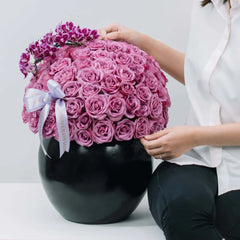 Elegant pink rose and mini orchid arrangement in black vase, ideal for flower delivery.