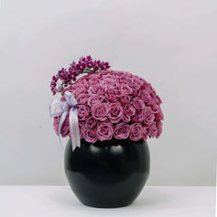 Elegant bouquet of pink roses and mini orchids in black vase for flower delivery